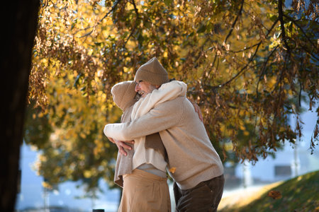 Portrait of beautiful senior couple during walk in autumn park. Elderly husband and wife are embracing each other.の写真素材