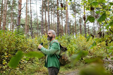 Tourist standing in the middle of nature, using binoculars to observe nature and wildlife in the...
