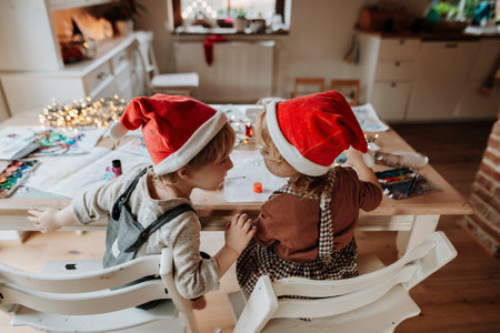 Rear view of siblings making holiday Christmas or christmas decorations at home. Creative activity for toddlers.の写真素材