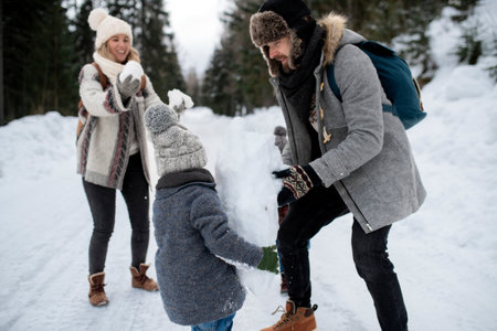 Portrait of boy enjoying winter holiday in the mountains with family, playing in snow, having snowball fight.の写真素材