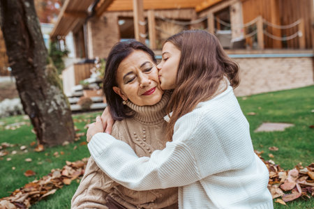 Young granddaughter kissing her grandmother on cheek, enjoying ttime together.の写真素材