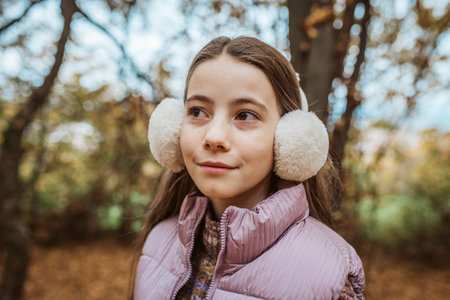 Outdoor portrait of young girl with fluffy earmuffs on head.の写真素材