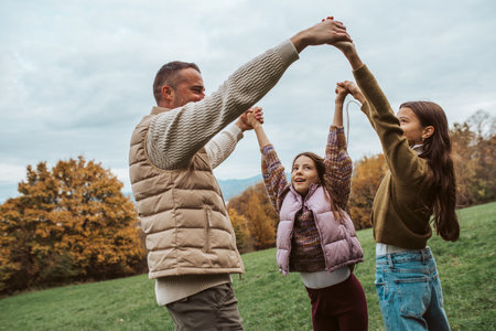Father dancing with daughters, holding hands.の写真素材