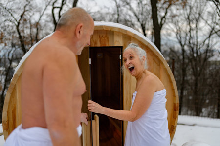 Senior couple using small sauna during cold winter day. Spa weekend getaway for elderly people.の写真素材