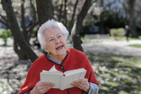 Beautiful elderly woman reading book in park.の写真素材