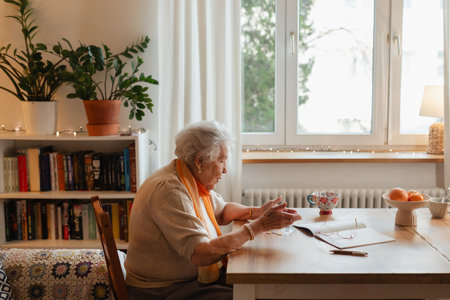 Side view of ederly woman looking sadly at few banknotes on table. Concept of financial concerns for seniors.の写真素材