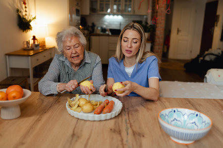 Portrait of elderly companion assistant and senior woman peeling apples. Home health care services.