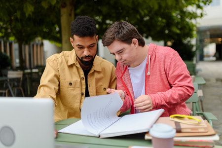 Young man with Down syndrome studyng with special educator teacher.の写真素材