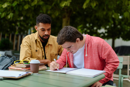 Young man with Down syndrome studyng with special educator teacher.の写真素材