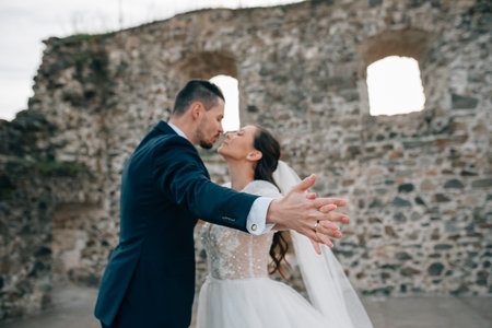 Bride and groom holding hands and kissing. Wedding couple standing outside near ruins.の写真素材