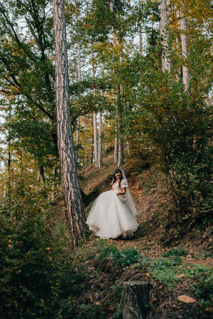 Bride walking through forest in her wedding dress.の写真素材