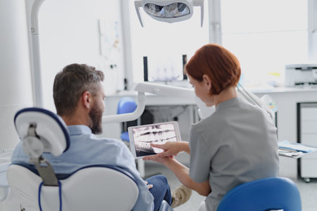 Female dentist showing x-ray to patient in dental clinic during anual check-up.