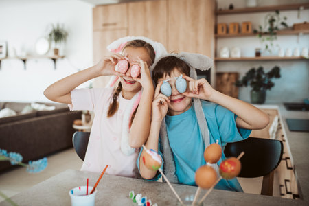 Girl and boy holding decorated easter eggs in front of eyes.の写真素材