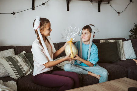Little girl gifting large Easter egg to young boy.
