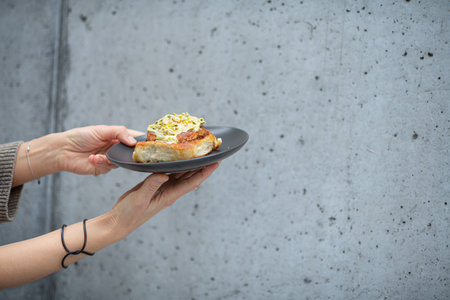 Close up of hands holding plate with cinnamon roll.の写真素材