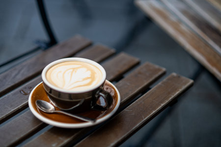 Cup of cappuccino with latte art on wooden table, cozy cafe setting.の写真素材