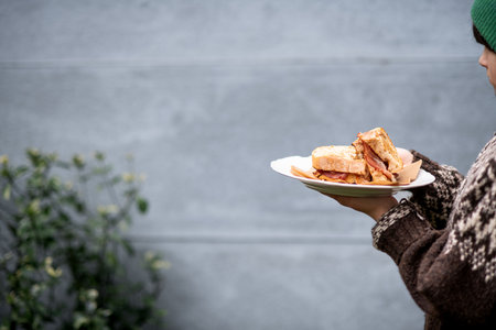 Girl holding plate with homemade baked bacon sandwich.の写真素材