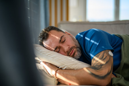 Man with CGM sensor on arm sleeping on sofa.の写真素材