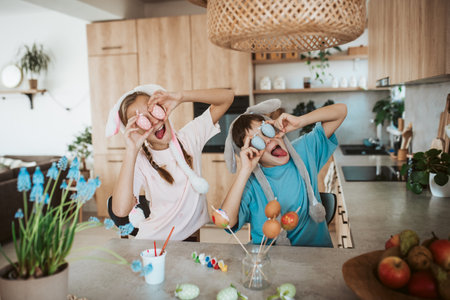 Siblings holding decorated easter eggs in front their eyes.