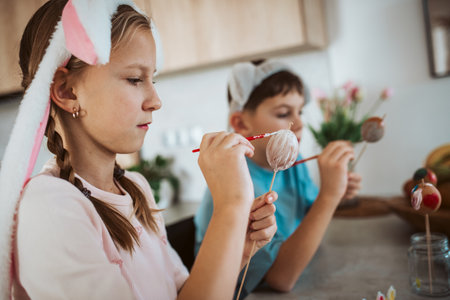 Girl and boy paiting eggs for easter, wearing bunny ears.の写真素材