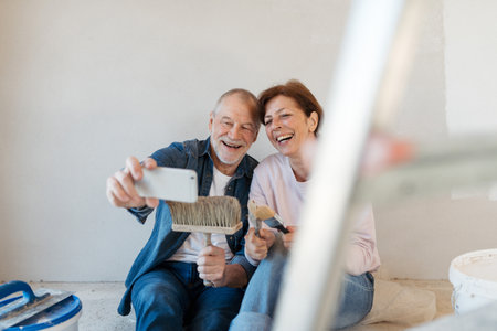 Senior couple taking break during their home renovation, taking a selfie.の写真素材
