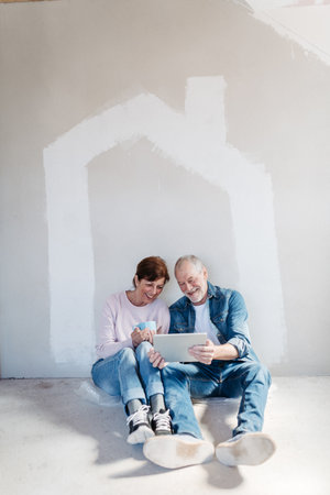 Senior couple renovating their home, browsing for inspirations on tablet.の写真素材