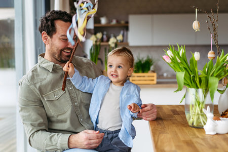 Father and little boy holding easter whip from willow branches, decorated with ribbons.
