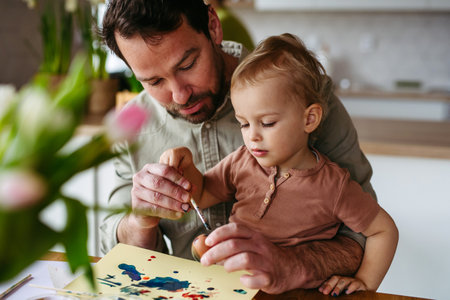 Little boy and father painting eggs with brush and easter egg dye.