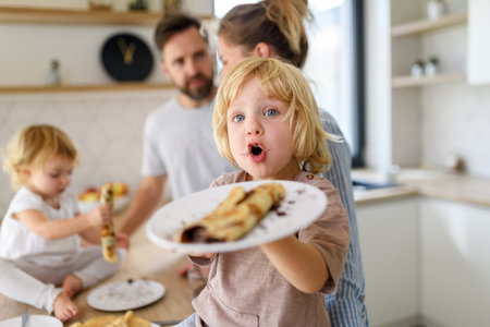 Young family making pancakes together. Parents and children in kitchen, spending weekend day indoors.の写真素材
