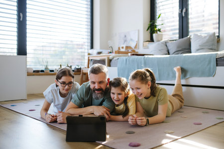 Portrait of father with three daughters watching tv show on tablet.