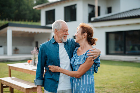 Older married couple embracing in a garden.の写真素材
