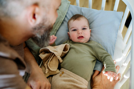 Father putting the baby to sleep, lying next to him in the crib.