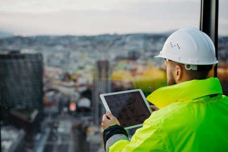 Rear view of construction site manager using digital tablet to inspect building progress.の写真素材