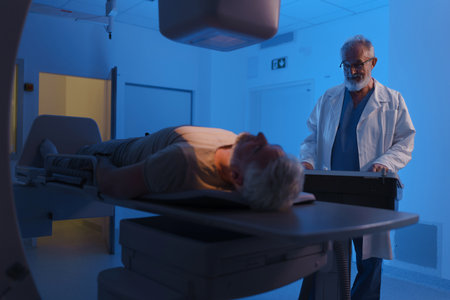Male patient undergoing X-ray examination using tilting radiographic wall stand.