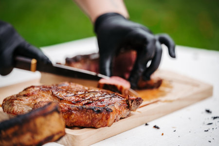 Chef slicing juicy grilled steak on wooden cutting board.
