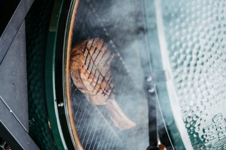 Grilling juicy Tomahawk steak on barbecue grill with smoke rising.の写真素材