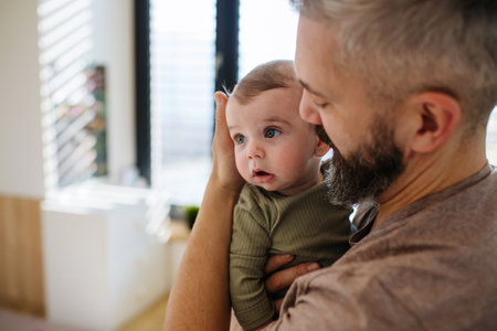 Portrait of father holding baby son in arms.