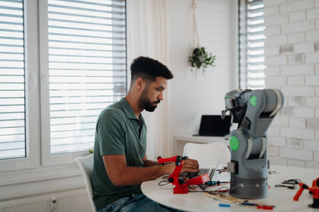 Side view of engineer building and programming a robotic arm at home.の写真素材