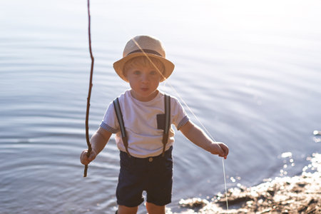A small toddler boy standing by a lake at sunset. Space.の写真素材
