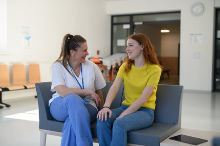 Nurse talking with teenage patient in hospital waiting room.の写真素材