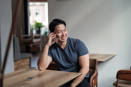 Confident man having phone call at cafe table.の写真素材