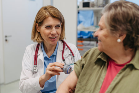 Female doctor applying CGM sensor to senior patients armの写真素材