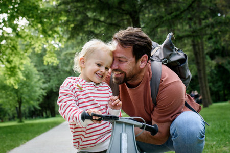 Father encourages son riding balance bike in parkの写真素材