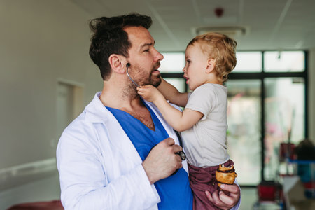 Handsome doctor holding young pediatric patient in arms.の写真素材