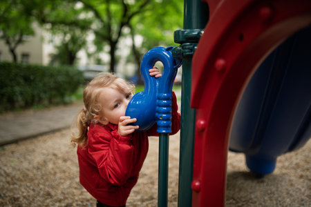Curious girl peeking through playground tubeの写真素材