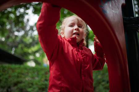 Child in red coat at play area.