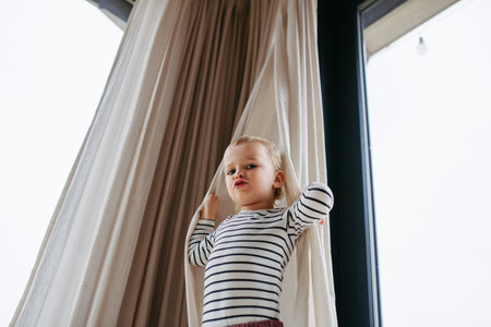 Adorable toddler boy playing hide and seek at home.の写真素材