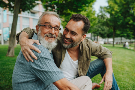 Portrait of handsome mature man and his older father hugging each other.