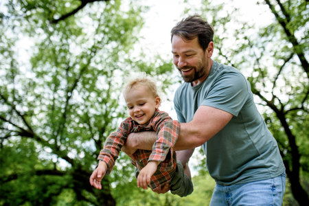 Father playing with toddler son outdoors in parkの写真素材