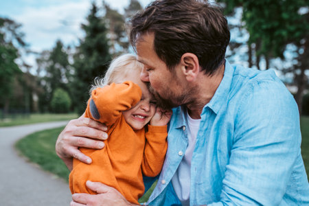 Father comforting young son during emotional moment in parkの写真素材